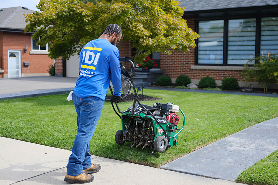 IDI employee aerating lawn