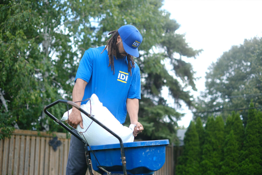 IDI employee pouring fertilizer