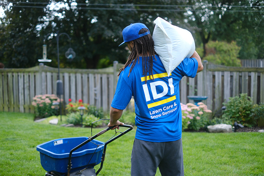 Close up of IDI employee applying fertilizer